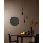 Ein moderner Essbereich verfügt über einen runden Spiegel an einer beigen Wand, mit drei Hängeleuchten - Tulpe Rondell über einem Tisch und schwarzen Stühlen. Auf dem Tisch stehen eine Vase mit Trockenblumen, eine dekorative Schale mit brennenden Kerzen und ein schwarzer Becher.