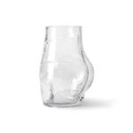 Die Vase „Glass Bum“ ist klar und hat eine einzigartige, asymmetrische Form mit einer Ausbuchtung auf einer Seite und steht auf einem schlichten weißen Hintergrund.