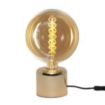 Der Leuchtenfuß - Felix von Licht Factory verfügt über eine runde, transparente, goldene Glühbirne mit einem spiralförmigen Glühfaden, die elegant auf einem glänzenden, goldenen zylindrischen Sockel montiert und durch ein schlankes, schwarzes Netzkabel ergänzt wird.