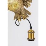 Die Pendelleuchte - Hedwig besteht aus einer detailreichen Eulenskulptur aus Messing, die eine Leuchte hält. Die Krallen der Eule greifen einen schwarzen Draht, der mit einer goldfarbenen Lampenfassung verbunden ist. Das Ganze wird elegant vor einem schlichten weißen Hintergrund präsentiert.