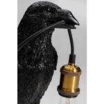 Die Tischleuchte-Skulptur „Black Crow“ hält vor einem schlichten weißen Hintergrund eine goldene Glühbirnenfassung mit einem schwarzen Kabel in ihrem Schnabel, Glühbirne nicht im Lieferumfang enthalten.