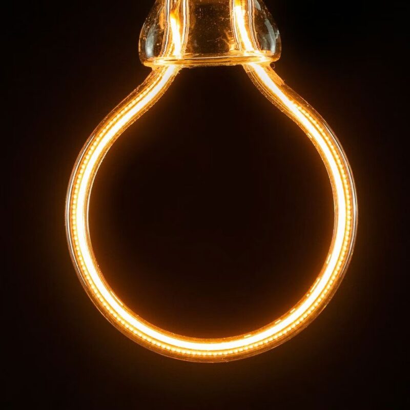 Nahaufnahme eines glühenden Glühfadens in einem runden, transparenten Leuchtmittel - Artlight Bulb 6,5W dimmbar 8,5cm, das warmes, orangefarbenes Licht vor einem dunklen Hintergrund ausstrahlt. Die elegante Schleife des Glühfadens betont die runde Form der Glühbirne.