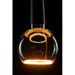 Eine Nahaufnahme des Leuchtmittels - Floatlight Globe 4W dimmbar gold Ø15cm zeigt sein beleuchtetes, kugelförmiges Glas mit einem leuchtenden Glühfaden im Inneren. Die Glühbirne strahlt vor einem dunklen Hintergrund ein warmes bernsteinfarbenes Licht aus und hebt so ihre reflektierende Oberfläche und moderne Eleganz hervor.