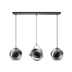 Drei moderne Naru Pendelleuchten mit kugelförmigen Glasschirmen hängen an einer rechteckigen schwarzen Deckenhalterung. Das zentrale Licht ist schräg geneigt und verleiht dem Arrangement eine künstlerische Note. Das reflektierende Glas besticht durch einen metallischen Glanz.