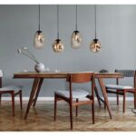 Ein modernes Esszimmer mit einem Holztisch für vier Personen. Darüber hängen vier Bubble-Pendelleuchten mit Glasschirmen von der Decke. Der Raum verfügt über einen Holzboden im Fischgrätmuster, graue Wände und minimalistisches Dekor, darunter eine Vase mit Blumen auf dem Tisch.