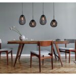 Ein Esszimmer verfügt über einen Holztisch mit vier Stühlen, die alle mit gestreiften Kissen ausgestattet sind. Er wird von einer schwarzen Pendelleuchte - Bubble 4er beleuchtet, die vor einer hellgrauen Wand und einem Fischgrätholzboden steht. Auf der Tischplatte steht eine Blumenvase.