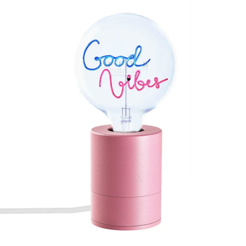 Die Leuchtenfuss - Statement Bulb rosa verfügt über einen rosa Sockel, der eine klare Glühbirne trägt, auf der in blauer und rosa Neonschrift der Schriftzug „Good Vibes“ leuchtet, verbunden mit einem weißen Netzkabel, alles vor einem schlichten weißen Hintergrund.