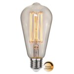 Die LED Kolben 3,8W 1800K dimmbar Ø6,4cm verfügt über ein sichtbares Glühfadendesign und einen Standard-Schraubsockel. Das diskrete Etikett bestätigt die Dimmerkompatibilität. Mit ihrer klassischen Tropfenform und dem warmen Licht verbindet diese Glühbirne auf wunderbare Weise Nostalgie mit moderner Technologie.