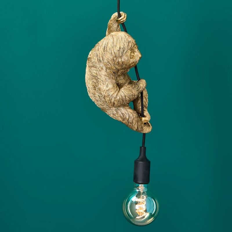 Die Pendelleuchte - Fauli besteht aus einer goldenen Faultierfigur, die an einer schwarzen Kordel hängt und an der eine klare Glühbirne hängt, die vor einem türkisfarbenen Hintergrund ein warmes Licht ausstrahlt.