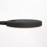Seitenansicht der Stehleuchte - Aike, einer minimalistischen LED-Schreibtischlampe mit rundem, schwarzem Kopf und dünnem Profil. Sie hat eine matte Oberfläche und einen Einschaltknopf oben, der sich elegant von einem schlichten weißen Hintergrund abhebt.