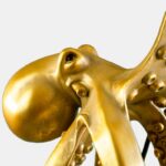 Nahaufnahme der Tischleuchte – Oktopus-Skulptur. Sie zeigt komplizierte Details wie strukturierte Haut, hervorstehende Augen und teilweise sichtbare Tentakeln vor einem schlichten hellgrauen Hintergrund und betont die Kunstfertigkeit dieses einzigartigen bronzefarbenen Stücks.