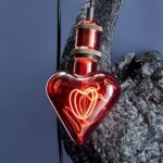 Eine Leuchtmittel-Glühbirne (Red Heart) mit glühendem Glühfaden hängt vor einer schwarzen Schwanenskulptur vor einem blauen Hintergrund.