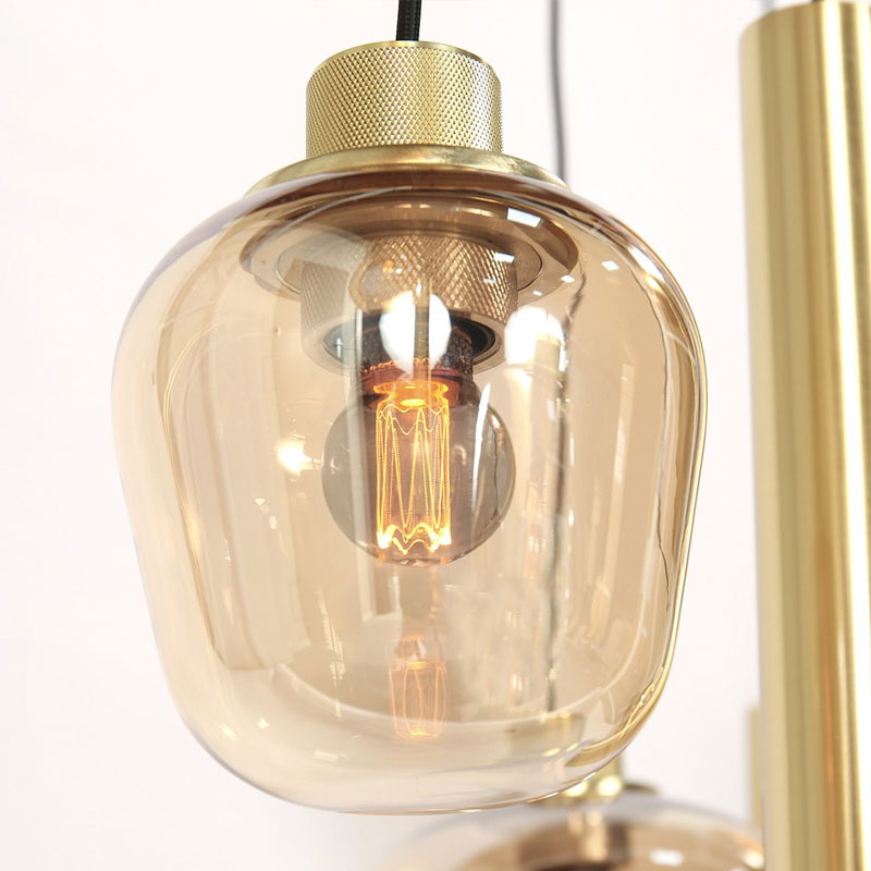 Nahaufnahme der Pendelleuchte Lucy 2.0 - 9er im Vintage-Stil mit freiliegender Glühlampe aus transparentem, bernsteinfarbenem Glas. Die Leuchte hat metallische Akzente und strahlt ein warmes Licht aus. Nahaufnahme der Pendelleuchte Lucy 2.0 - 9er im Vintage-Stil mit freiliegender Glühlampe aus transparentem, bernsteinfarbenem Glas. Die Leuchte hat metallische Akzente und strahlt ein warmes Licht aus.