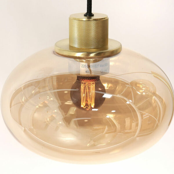 Eine Nahaufnahme der Pendelleuchte - Lucy 2.0 - 9er zeigt ein modernes Design mit einer freiliegenden Glühlampe, die in einem runden, durchscheinenden Schirm aus bernsteinfarbenem Glas eingeschlossen ist. Die Leuchte hat eine metallische Oberseite und strahlt im eingeschalteten Zustand ein warmes Licht aus.
