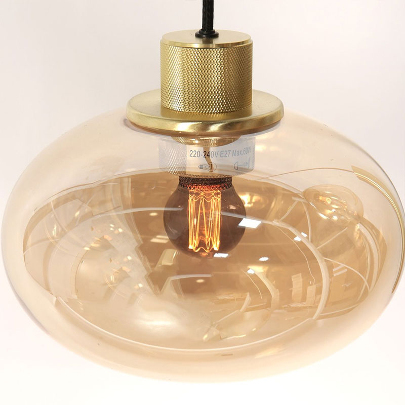 Eine Nahaufnahme der Pendelleuchte - Lucy 2.0 - 9er zeigt ein modernes Design mit einer freiliegenden Glühlampe, die in einem runden, durchscheinenden Schirm aus bernsteinfarbenem Glas eingeschlossen ist. Die Leuchte hat eine metallische Oberseite und strahlt im eingeschalteten Zustand ein warmes Licht aus. Eine Nahaufnahme der Pendelleuchte - Lucy 2.0 - 9er zeigt ein modernes Design mit einer freiliegenden Glühlampe, die in einem runden, durchscheinenden Schirm aus bernsteinfarbenem Glas eingeschlossen ist. Die Leuchte hat eine metallische Oberseite und strahlt im eingeschalteten Zustand ein warmes Licht aus.