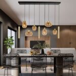 Modernes Esszimmer mit einem rechteckigen Tisch und sechs schwarzen Drahtgestellstühlen. Darüber hängen neun eklektische Pendelleuchten – Lucy 2.0, die den Raum elegant beleuchten. Der Raum enthält außerdem ein graues Sofa, eine minimalistische Pflanze und Holzakzente.