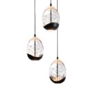 Drei Pendelleuchten - Tara 3er Rondell mit schwarzem Sockel und Schirmen aus klarem Strukturglas hängen von der Decke und verbreiten ein sanftes Licht. Ihr blasenartiges Design hebt sich elegant von einem weißen Hintergrund ab.