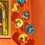 bunte pendellgläser vor einer orangenen wand mit einem kleinen ausschnitt von einem bild