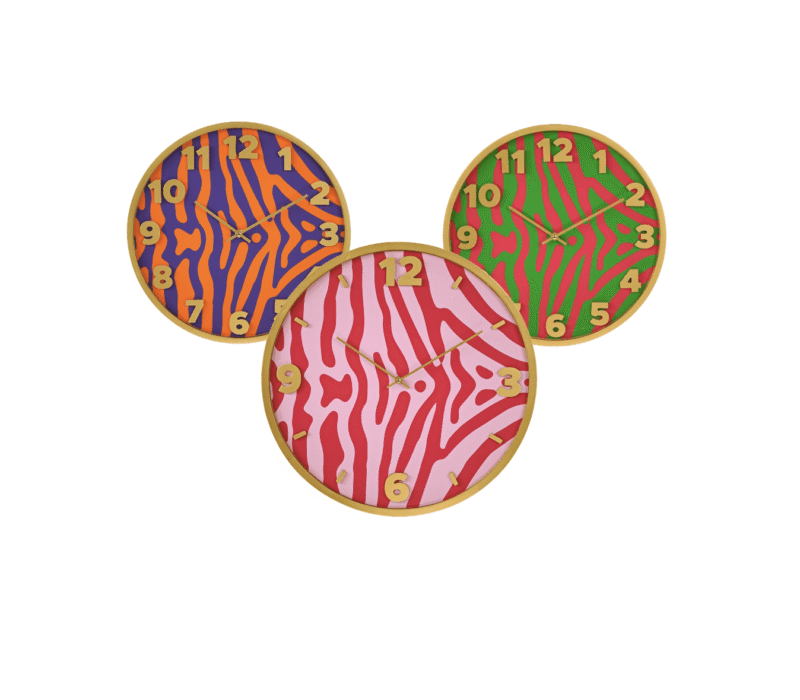 Drei dekorative Wanduhren vom Typ Safari sind in einer dreieckigen Formation angeordnet, jede mit einem einzigartigen Zebrastreifenmuster: eine ist orange und lila, eine andere ist rosa und rot und die dritte ist grün und gelb, alle mit goldfarbenen Rändern.