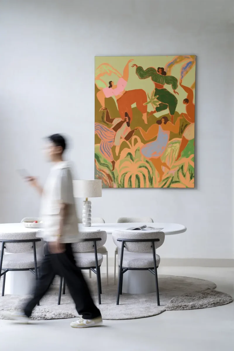 Eine verschwommene Gestalt geht an einem modernen Essbereich mit einem runden Tisch und Stühlen auf einem runden Teppich vorbei, während an der Wand im Hintergrund „Wandbild – Spring Frolic“ hängt, ein abstraktes Gemälde mit lebendigen Figuren und Blättern.