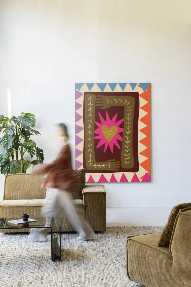 Eine Person geht an einem gemütlichen Wohnzimmer vorbei, in dem ein großes „Wandbild - Hug“ mit abstrakten Mustern und einer Sternform hängt, die das Motto „No Risk, No Story“ verkörpert. Im Zimmer stehen ein grüner Sessel, ein beiges Sofa, ein kleiner runder Tisch und eine Topfpflanze.