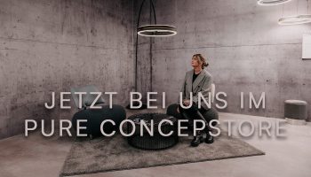 Frau sitzt auf einem Sessel im Hintergrund ist eine Bogenlampe zu sehen.